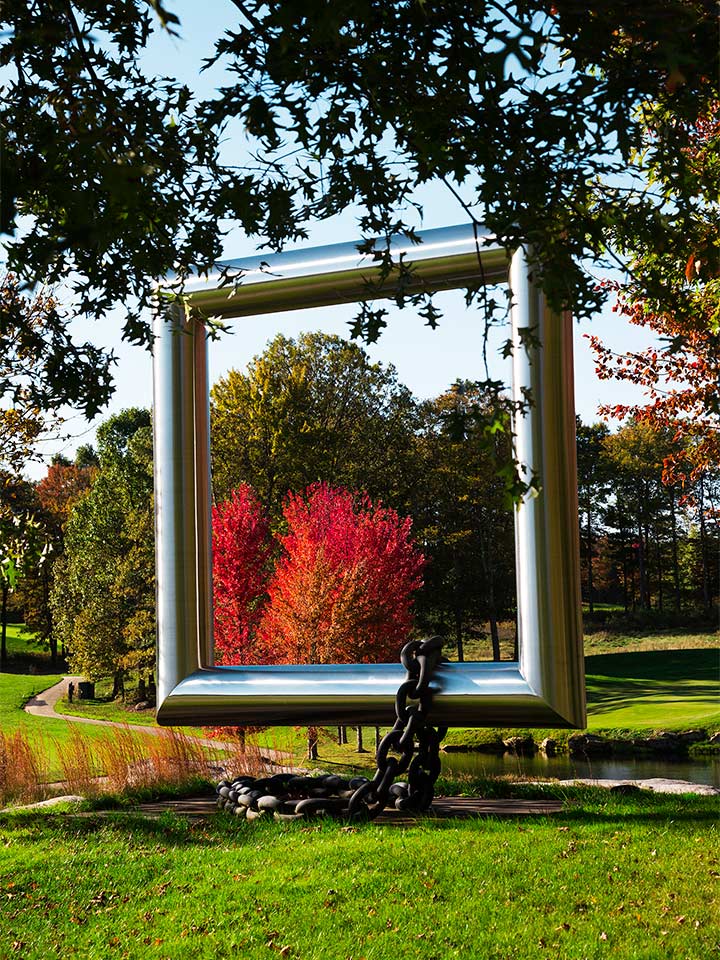 above ground silver 3D square sculpture with chain draped over the bottom outside